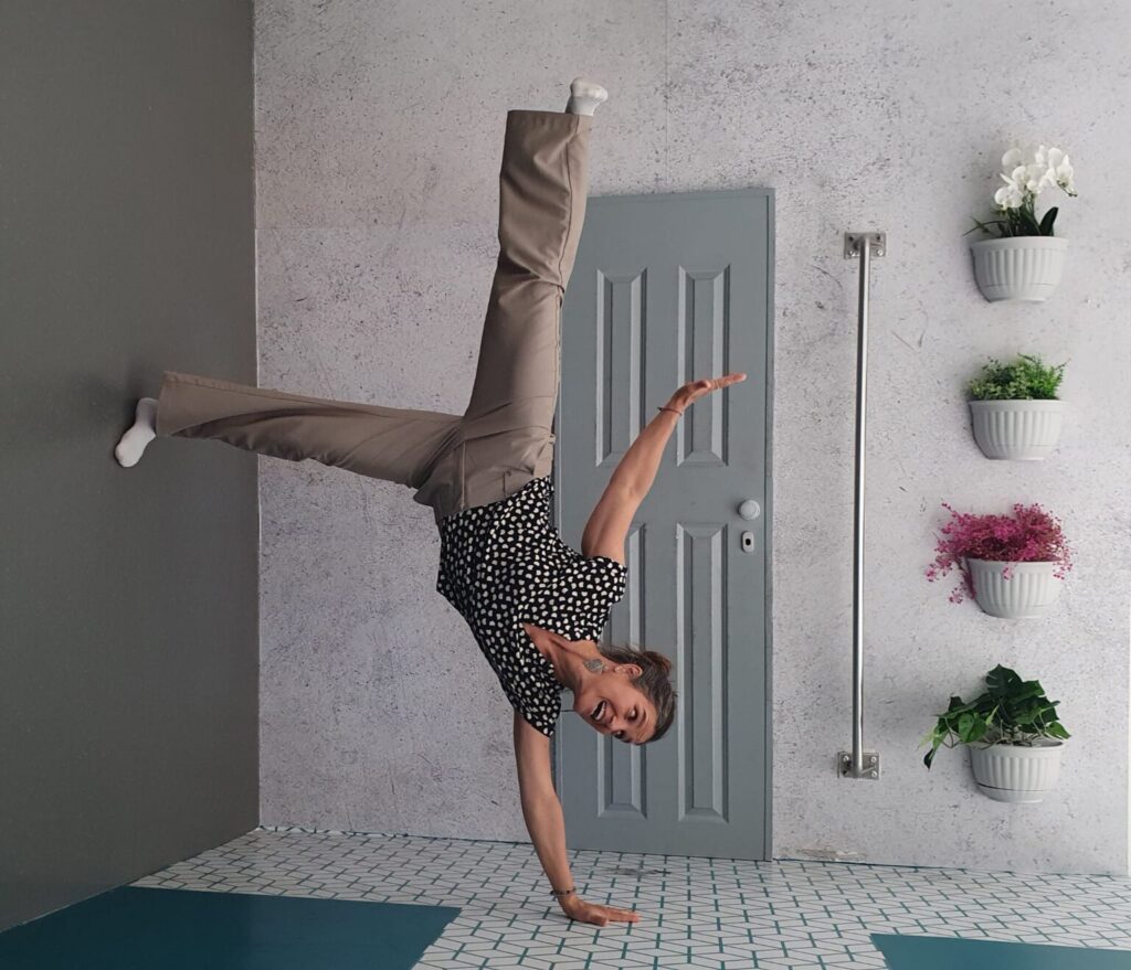 Eine Person macht einen einarmigen Handstand (Breakdance-Move) in einem modern eingerichteten Raum