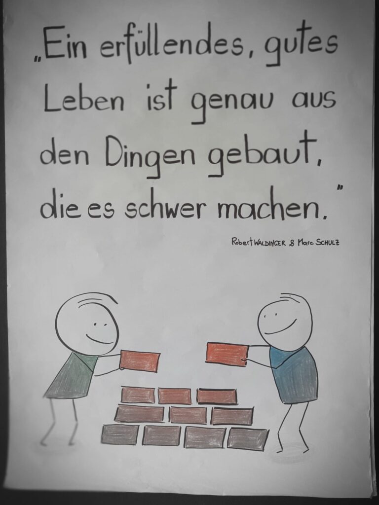 Eine handgezeichnete Skizze mit zwei Strichmännchen, die eine Mauer bauen, darüber ein handschriftliches Zitat auf Deutsch: „Ein erfüllendes, gutes Leben ist genau aus den Dingen gebaut, die es schwer machen.“